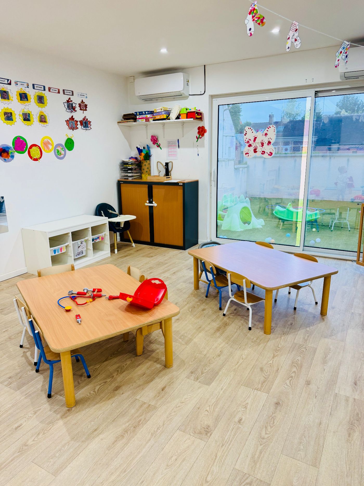 Salle d'activités lumineuse de la micro-crèche avec petites tables et vue sur l'extérieur